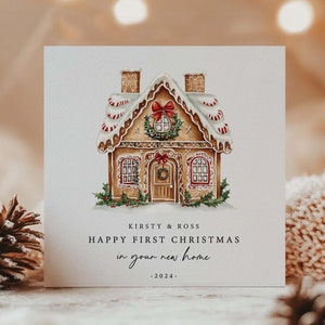 May include: A Christmas card featuring a watercolor illustration of a gingerbread house with snow-covered roof and festive decorations. The card reads "Happy First Christmas in your new home - 2024".