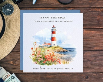 May include: A birthday card with a watercolor illustration of a lighthouse on a rocky shore with red flowers. The card says "Happy Birthday to my wonderful friend Amanda" and "With love on your 50th Birthday".