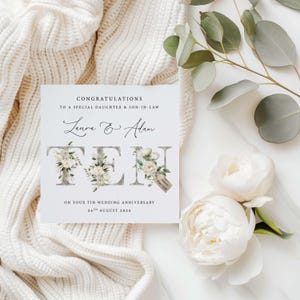 May include: A white card with a floral design and the text "Congratulations to a special daughter & son-in-law Laura & Alan Ten years married On your Tin Wedding Anniversary 24th August 2025"