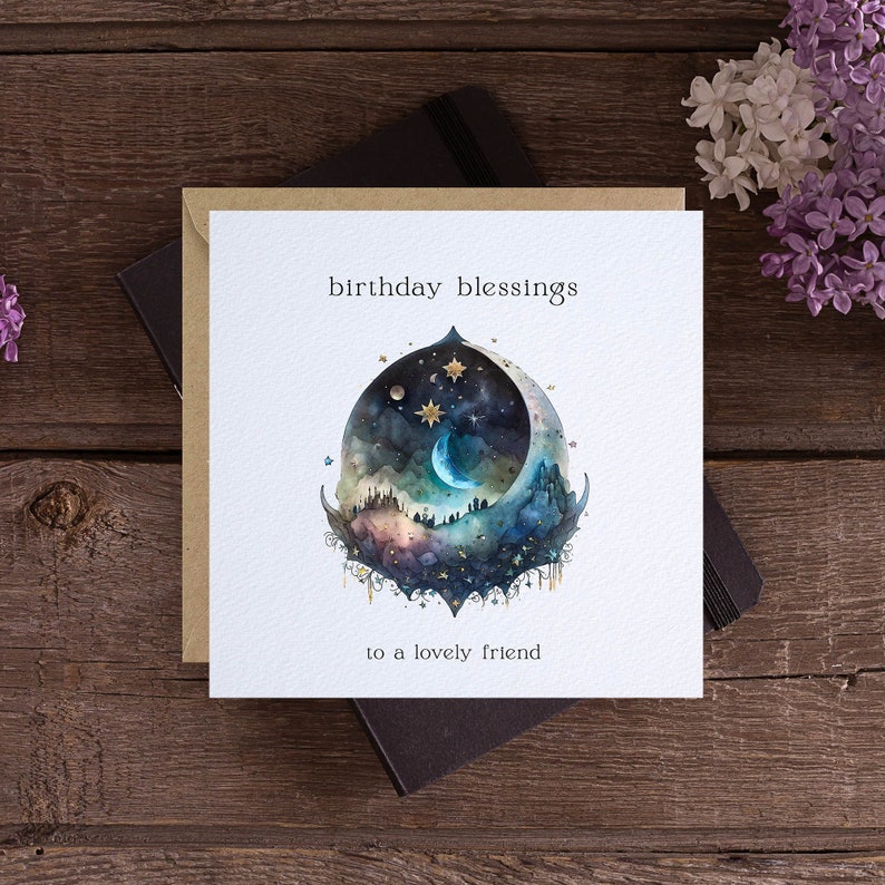 Pu&ograve; includere: Un biglietto bianco con un'illustrazione ad acquerello di una luna crescente, stelle e un cielo notturno. Il testo "birthday blessings to a lovely friend" &egrave; stampato sul biglietto.
