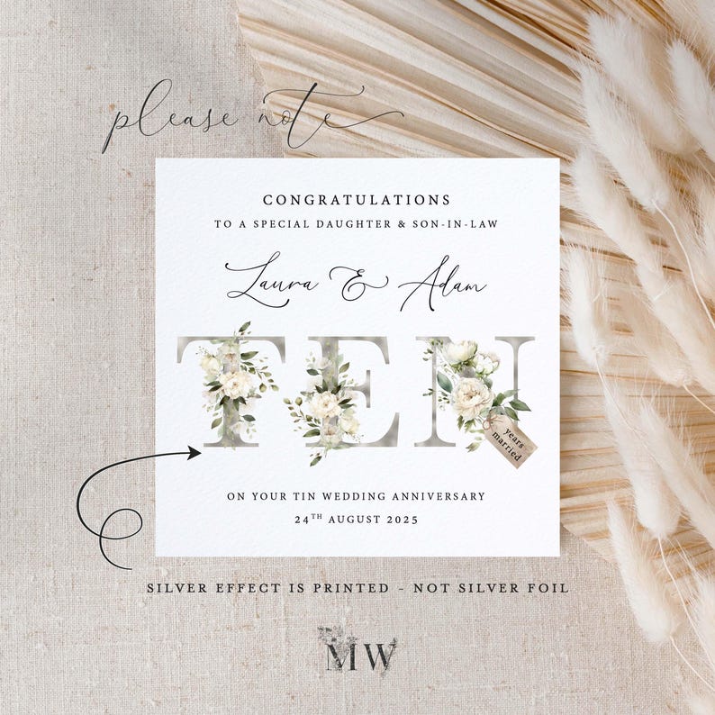 May include: A white card with a floral design spelling out the word "TEN" to celebrate a 10th wedding anniversary. The card reads "Congratulations to a special daughter & son-in-law Laura & Alan on your Tin Wedding Anniversary 24th August 2025. Silver effect is printed - not silver foil. MW"