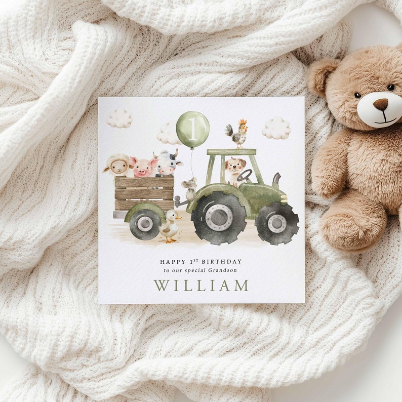 May include: A green tractor with a number one balloon attached to the side.  The tractor is carrying a variety of farm animals, including a pig, cow, sheep, mouse, and dog.  The text on the card reads "Happy 1st Birthday to our special Grandson WILLIAM".