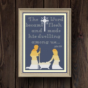May include: A framed cross-stitch design with a blue background and white text. The text reads "The Word became flesh and made his dwelling among us... John 1:14". The design also includes a silhouette of Joseph and Mary kneeling beside a manger.