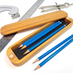 Display of the teak pencil case with lid open.  Pencils and rulers are next to it for display purposes