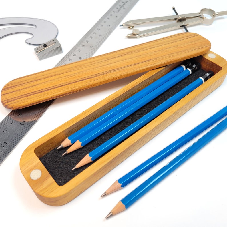 Display of the teak pencil case with lid open.  Pencils and rulers are next to it for display purposes