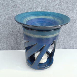 Könnte beinhalten: Blauer Keramik-Ölbrenner mit dekorativem Design. Der Brenner hat eine obere Schale für ätherische Öle und einen unteren Bereich für ein Teelicht.