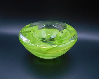 May include: A green glass bowl with a swirl design. The bowl is made of clear glass with a green tint and has a swirling pattern.