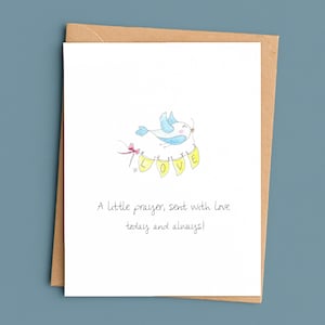 May include: A white greeting card with a watercolor illustration of a blue bird carrying a banner that spells "LOVE". The card is inside a brown envelope. The text on the card reads: "A little prayer, sent with love today and always!"