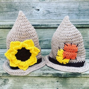 May include: Two crocheted scarecrow hats, one with a yellow sunflower and the other with orange and yellow patchwork. The hats are brown and beige with a brown brim. The text "Wyatt's Art Design" is visible below the hats.