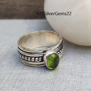 May include: A silver ring with a green gemstone and a beaded band.