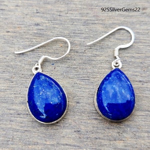 May include: A pair of silver teardrop earrings with blue lapis lazuli stones. The earrings have a simple design and are perfect for everyday wear.