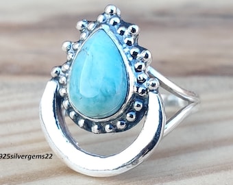 Può includere: Un anello d'argento con una pietra turchese a forma di lacrima incastonata in una montatura d'argento. L'anello ha una fascia a forma di mezzaluna con un design delicato.