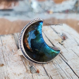 May include: A crescent moon shaped ring with a blue and green labradorite gemstone set in sterling silver.