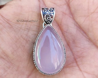May include: A teardrop-shaped pendant with a light pink gemstone set in a silver frame. The pendant has a detailed silver bail with a swirl design.