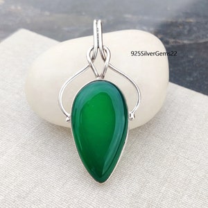 May include: A teardrop-shaped green gemstone pendant with a silver setting. The pendant features a delicate, intricate design with a knotted bail.