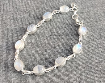 May include: A silver chain bracelet with oval-shaped moonstone beads. The bracelet has a lobster clasp closure.