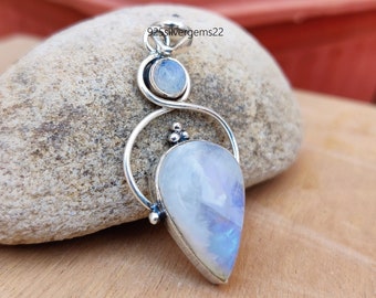 May include: A silver pendant with a teardrop-shaped moonstone and a smaller round moonstone. The pendant is set in a silver frame with a delicate design.