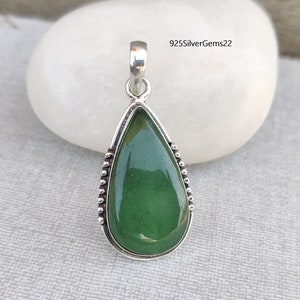 May include: A teardrop-shaped pendant with a green gemstone set in sterling silver. The pendant has a beaded border around the gemstone.
