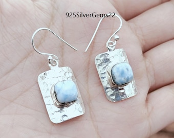 Pode incluir: Um par de brincos de prata com uma gema azul claro engastada em uma moldura de prata martelada. 925SilverGems22 está impresso na imagem.