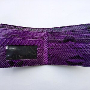 May include: A purple snakeskin wallet with a clear plastic ID window. The wallet is open and the inside is visible.