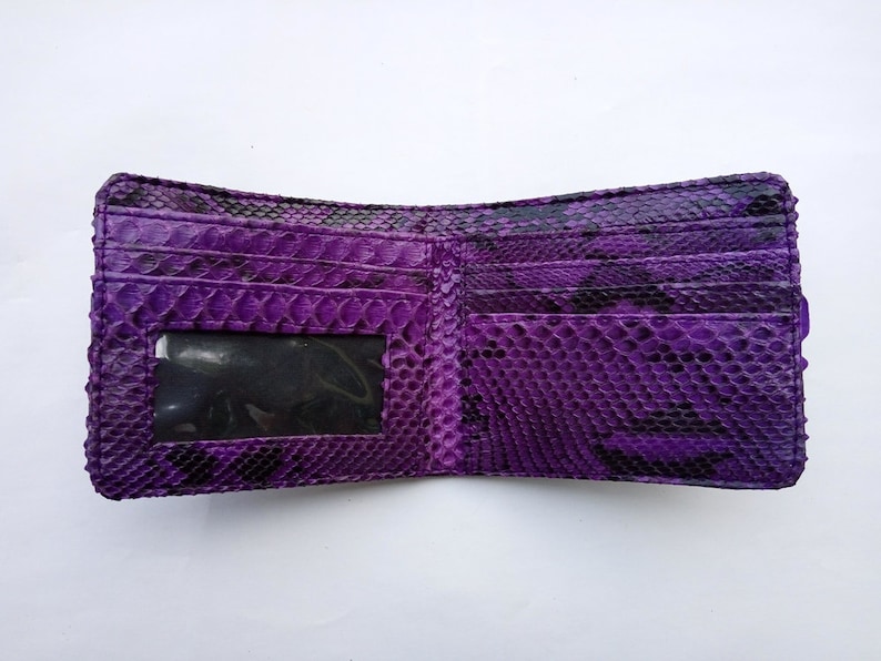 May include: A purple snakeskin wallet with a clear plastic ID window. The wallet is open and the inside is visible.
