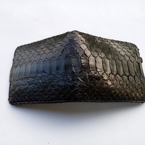 May include: A black leather wallet with a snakeskin pattern.