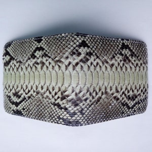 May include: A light brown snakeskin wallet with a black and white pattern.