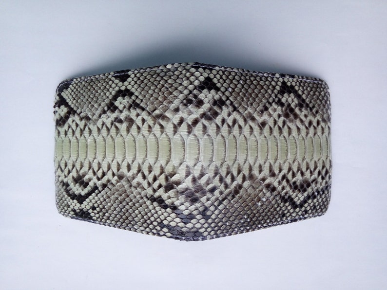 May include: A light brown snakeskin wallet with a black and white pattern.