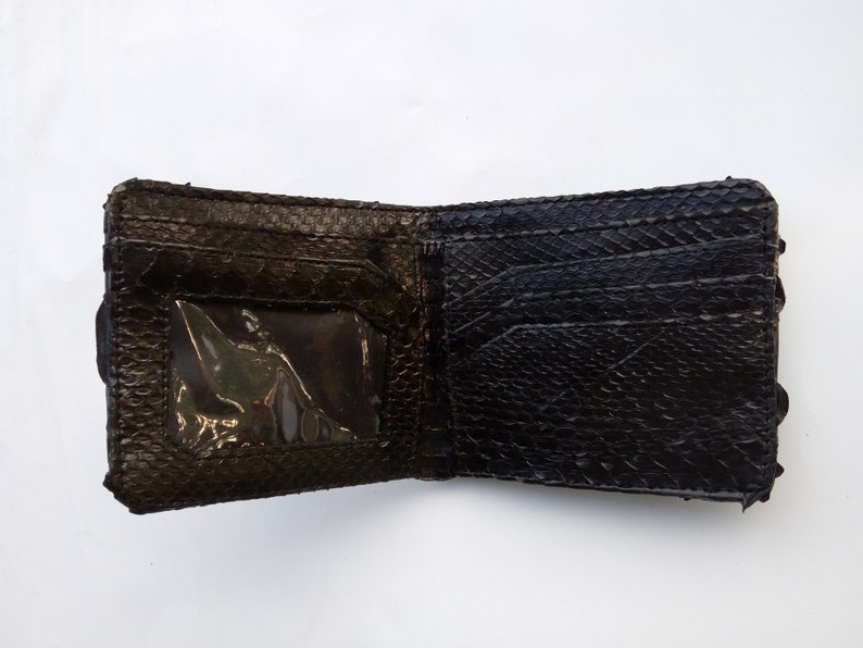May include: A black leather wallet with a textured surface and a clear plastic window for an ID card.