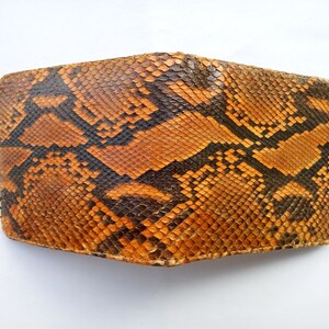 May include: A brown and black snakeskin wallet with a textured pattern.