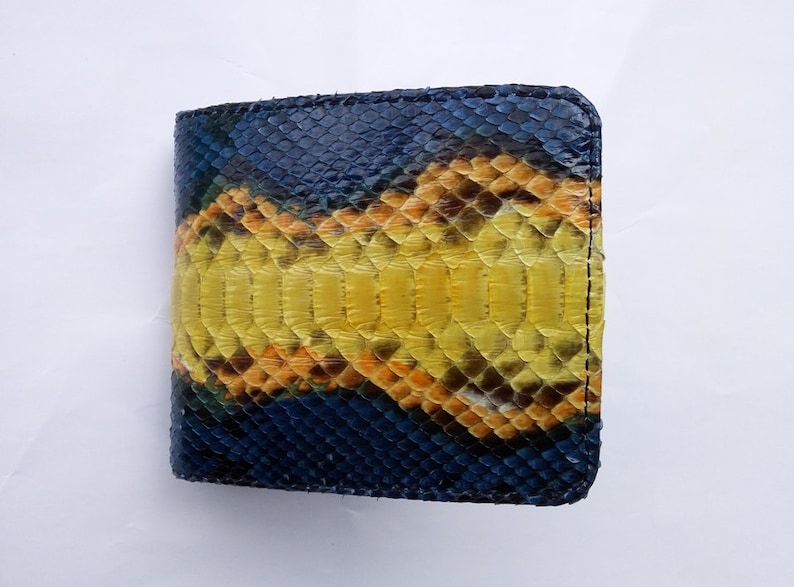 May include: A bi-fold wallet crafted from genuine snakeskin. The wallet features a striking pattern of navy blue, yellow, and brown scales. The edges are neatly stitched with black thread, creating a durable and stylish accessory.