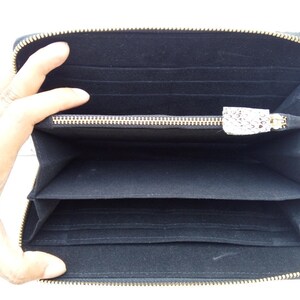 May include: Black zippered wallet with multiple interior compartments and a gold zipper.