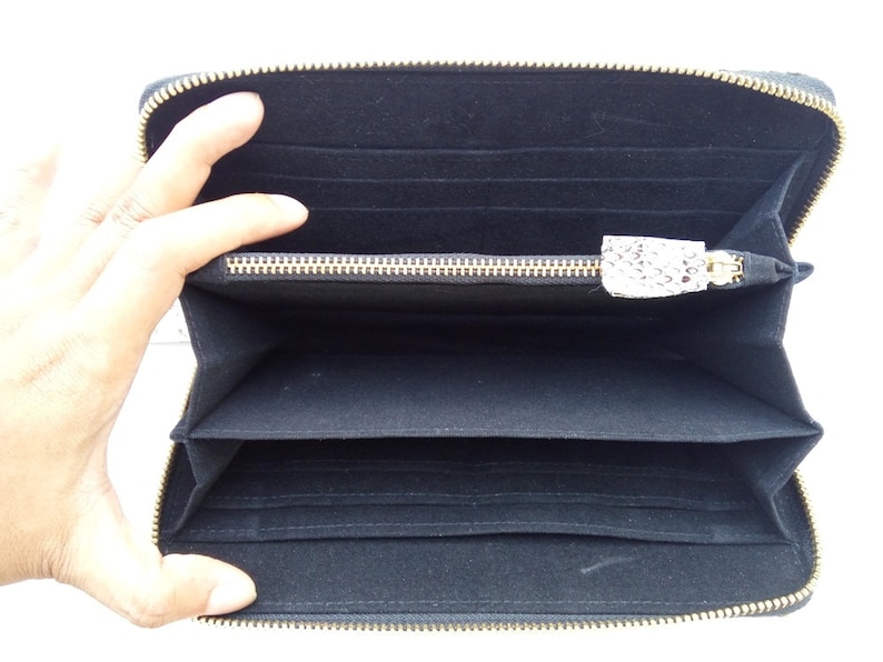 May include: Black zippered wallet with multiple interior compartments and a gold zipper.