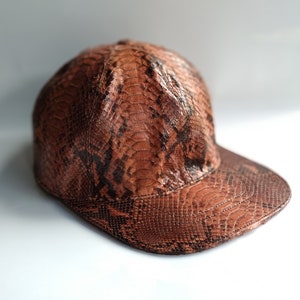 May include: A brown and black snakeskin baseball cap with a curved brim.