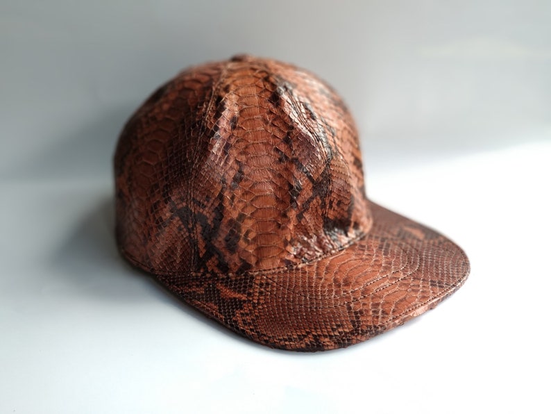 May include: A brown and black snakeskin baseball cap with a curved brim.