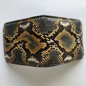 K&ouml;nnte beinhalten: Eine schwarze, braune und wei&szlig;e Schlangenleder-Geldb&ouml;rse mit einer strukturierten Oberfl&auml;che.