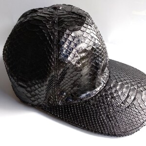 May include: A black snakeskin baseball cap with a curved brim.