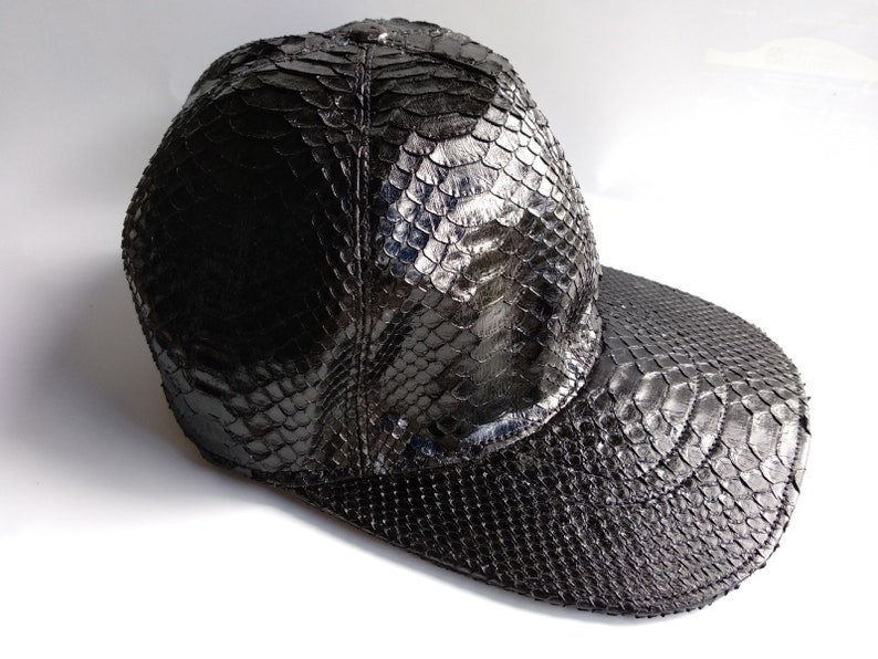 May include: A black snakeskin baseball cap with a curved brim.