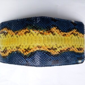 May include: A bi-fold wallet crafted from genuine snakeskin. The wallet features a striking pattern of blue, yellow, and orange scales. The design is symmetrical, with a central yellow stripe flanked by blue and orange sections. The texture of the snakeskin is clearly visible.