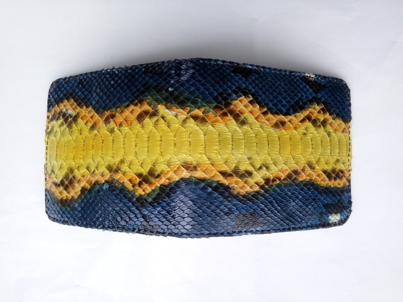 May include: A bi-fold wallet crafted from genuine snakeskin. The wallet features a striking pattern of blue, yellow, and orange scales. The design is symmetrical, with a central yellow stripe flanked by blue and orange sections. The texture of the snakeskin is clearly visible.