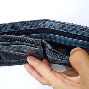 May include: A blue snakeskin wallet with a zippered closure and a clear plastic ID window.