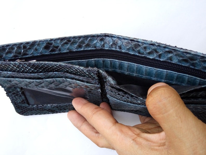 May include: A blue snakeskin wallet with a zippered closure and a clear plastic ID window.