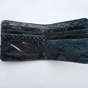 May include: A black leather wallet with a snakeskin pattern. The wallet has multiple card slots and a clear ID window.