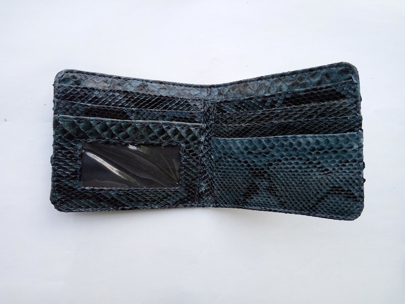May include: A black leather wallet with a snakeskin pattern. The wallet has multiple card slots and a clear ID window.