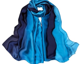 May include: A blue and navy ombre silk scarf. The scarf is made of a soft, flowing fabric and has a gradient design.