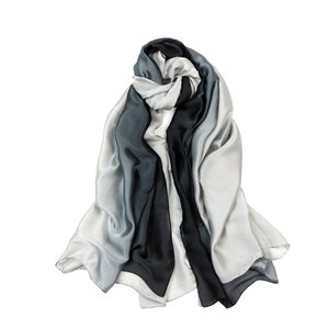 May include: A gray and black ombre silk scarf. The scarf is folded and tied in a knot.