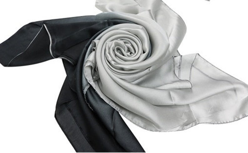May include: A black and white silk scarf with a gradient pattern. The scarf is folded into a rose shape.