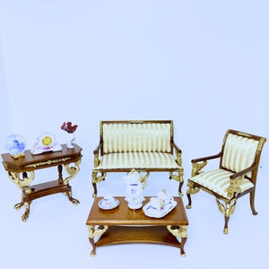 Puede incluir: Conjunto de muebles en miniatura para casa de muñecas. Incluye una mesa de madera con reloj y globo, un sofá, un sillón y una mesa de centro con un juego de té. Acentos dorados y tapicería a rayas.