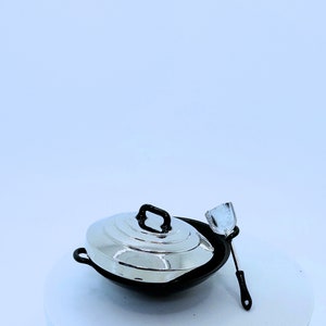 May include: A miniature black wok with a silver lid and a matching spatula. The wok has a black handle and a silver lid with a black handle. The spatula has a black handle and a silver blade. Kitchenware.