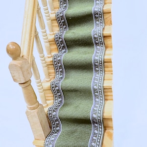 May include: A wooden staircase with a green and white patterned runner. The runner has a textured surface and a white border with a repeating leaf design.